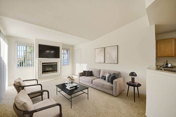a living room with a couch coffee table and chairs and a fireplace at Arroyo Villa Apartments, Thousand Oaks, CA